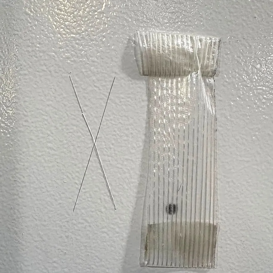 Corte em X sem desplacamento em pintura cinza texturizada e, ao lado, a fita retirada do corte, sem tinta aderida
