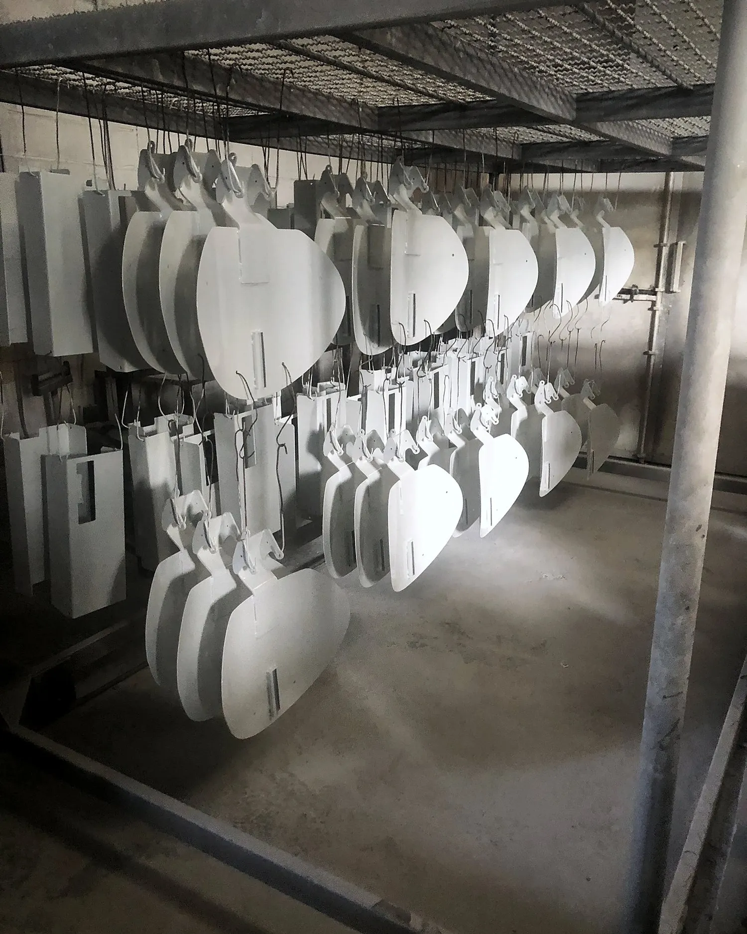 Peças brancas penduradas na linha de pintura