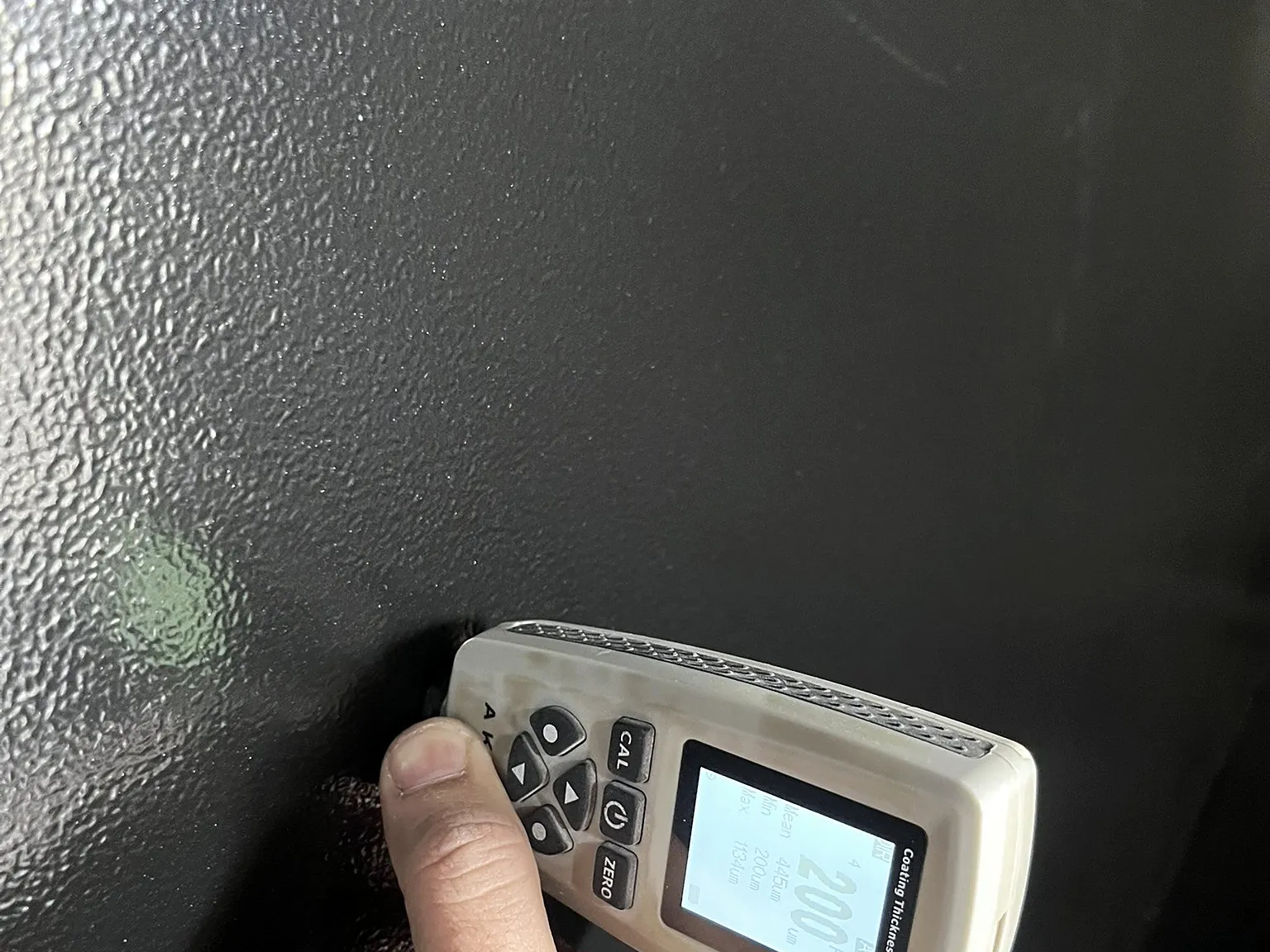 Medidor digital de camada sobre peça pintada em preto